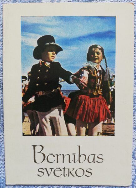 Bērni dejo latviešu tautastērpos. Bērnības svētkos. 1974. gada atklātne 10,5x15 cm Mākslinieks K. Goldmanis